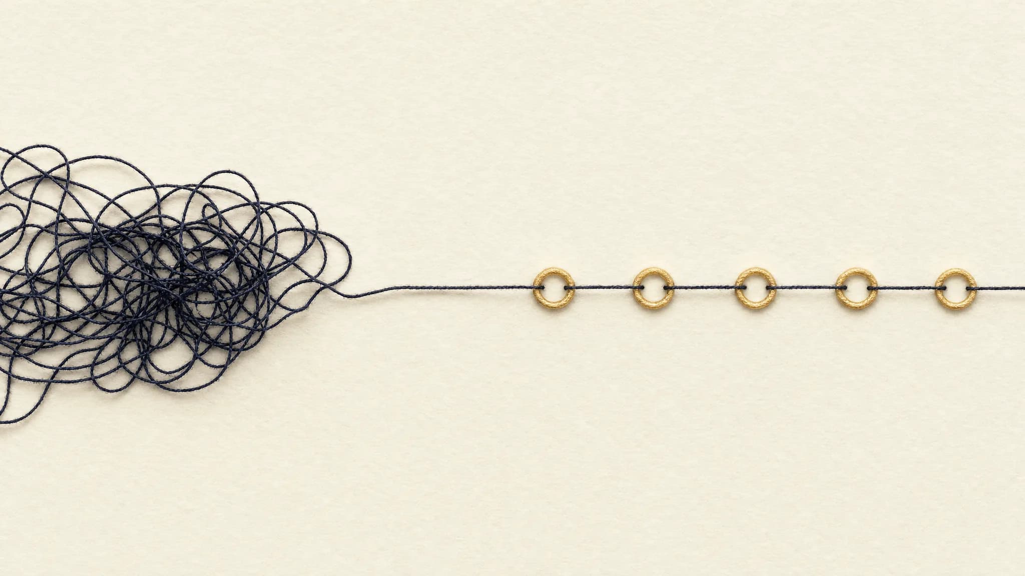 A tangled paper thread on cream paper resolving into a neat stitched line passing through a series of small gold rings, symbolising a messy process being organised into a clear workflow.